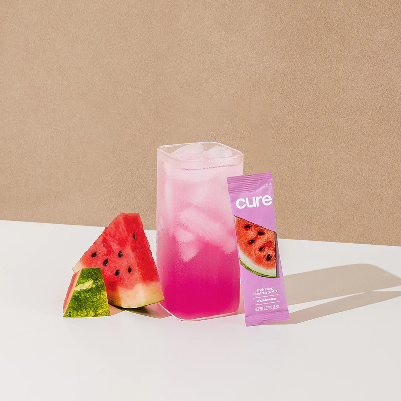 Pink iced drink with watermelon slices and a product label reading 'cure'